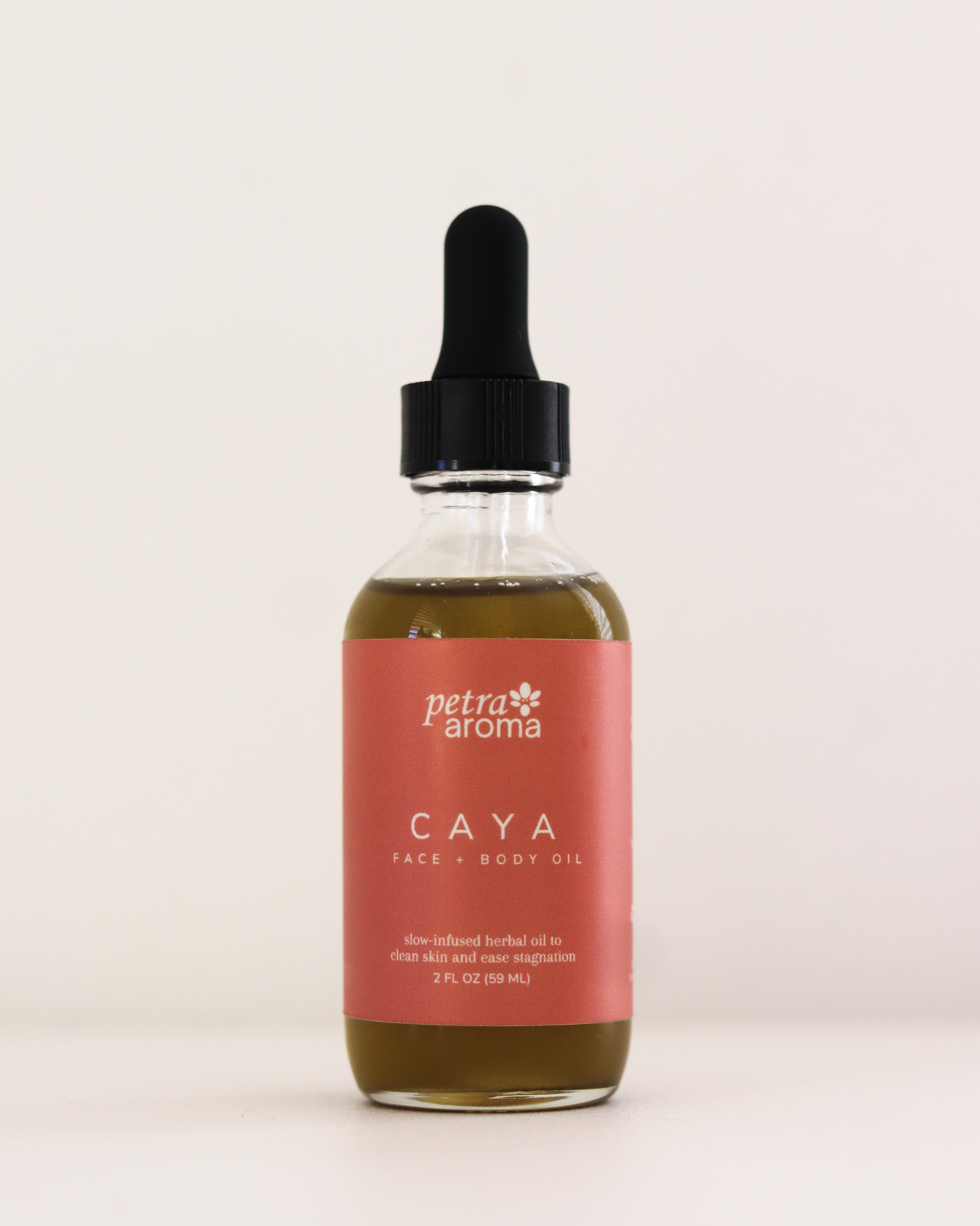 Bottle of Petra Aroma Caya hair product with a dropper on a light pink background