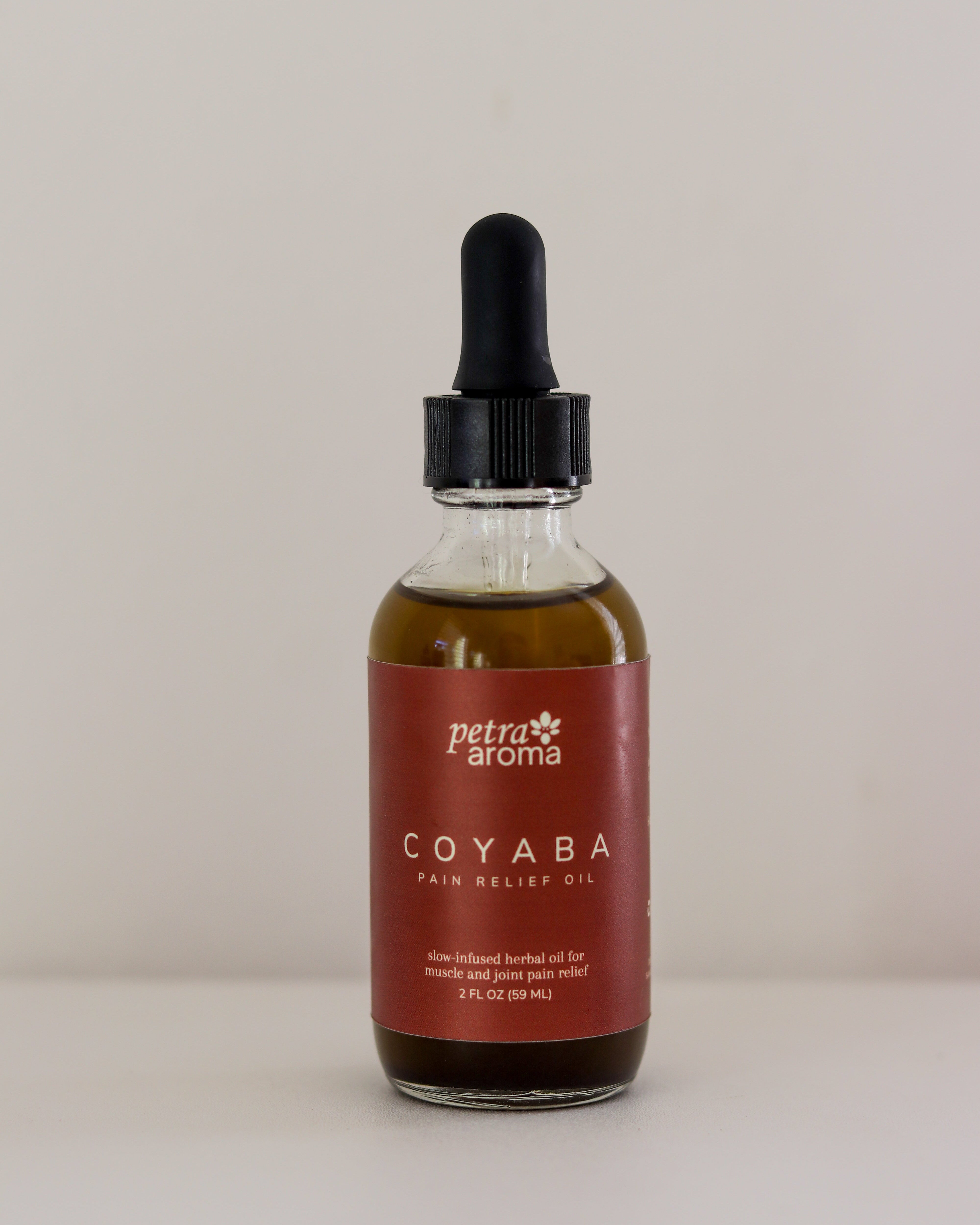 Bottle of petra aroha Coyaba pain relief oil on a beige background
