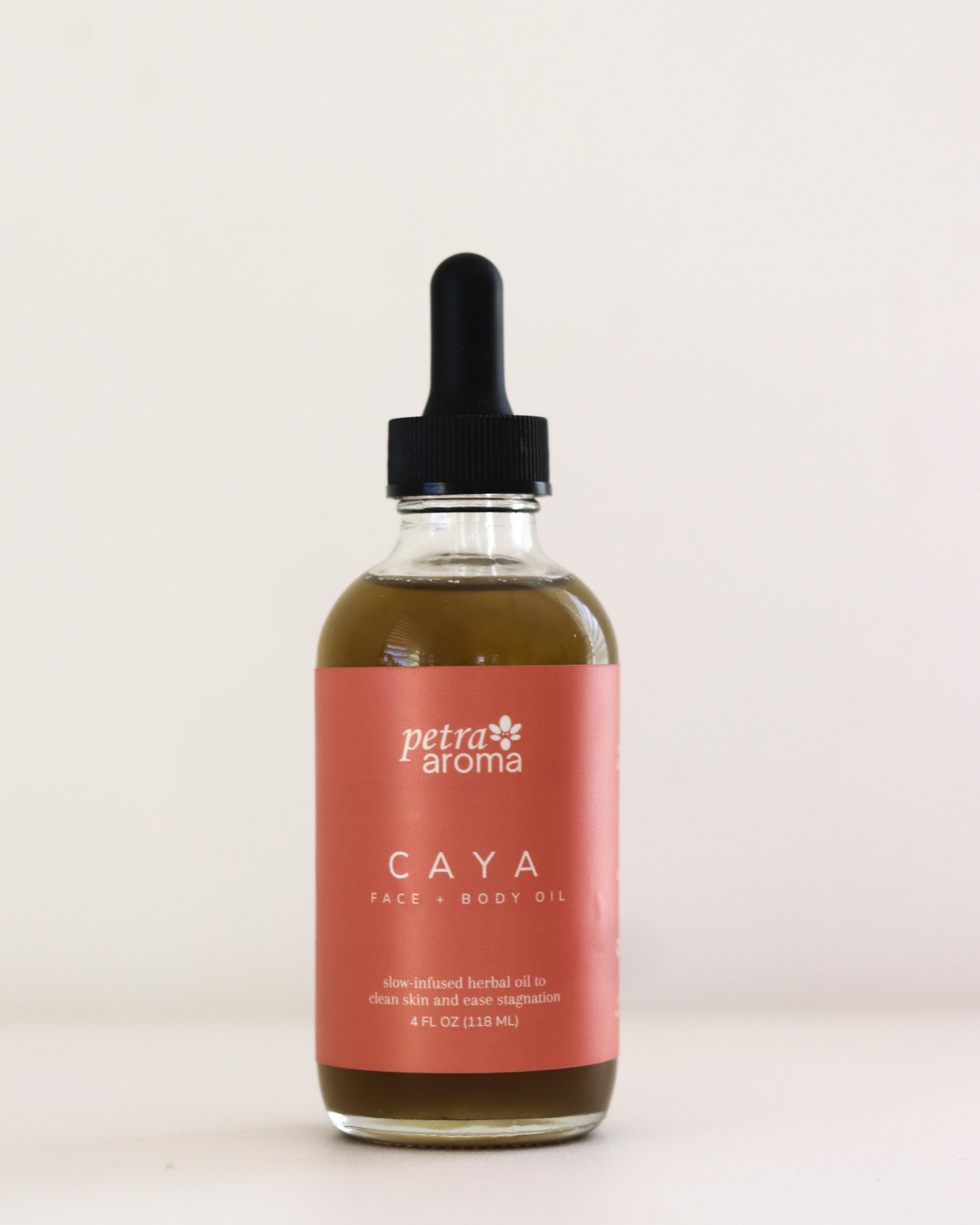 Bottle of Petra Aroma Caya body oil with a dropper on a light beige background