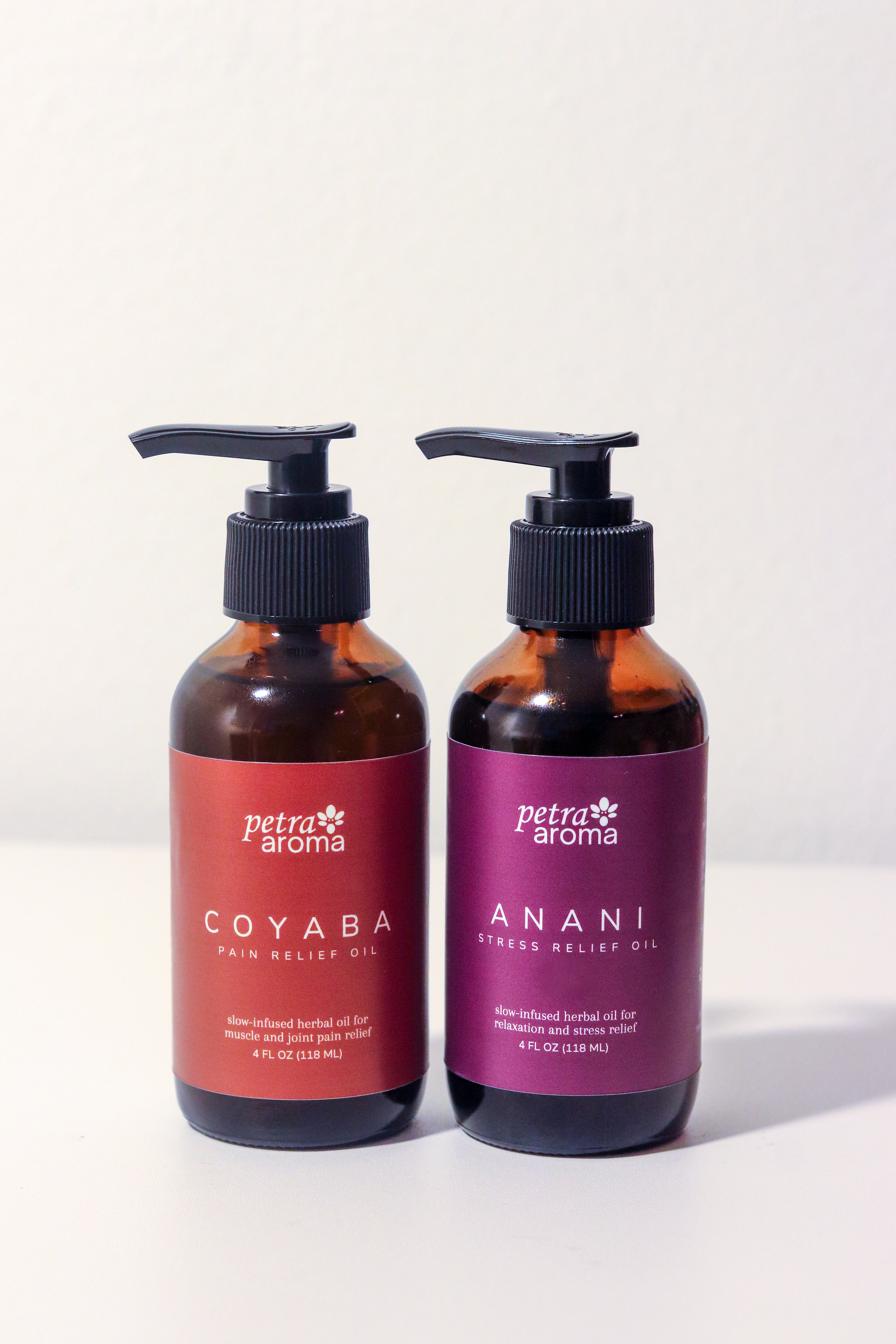 Two bottles of Petra Aroma oils, one red and one purple, on a white background.